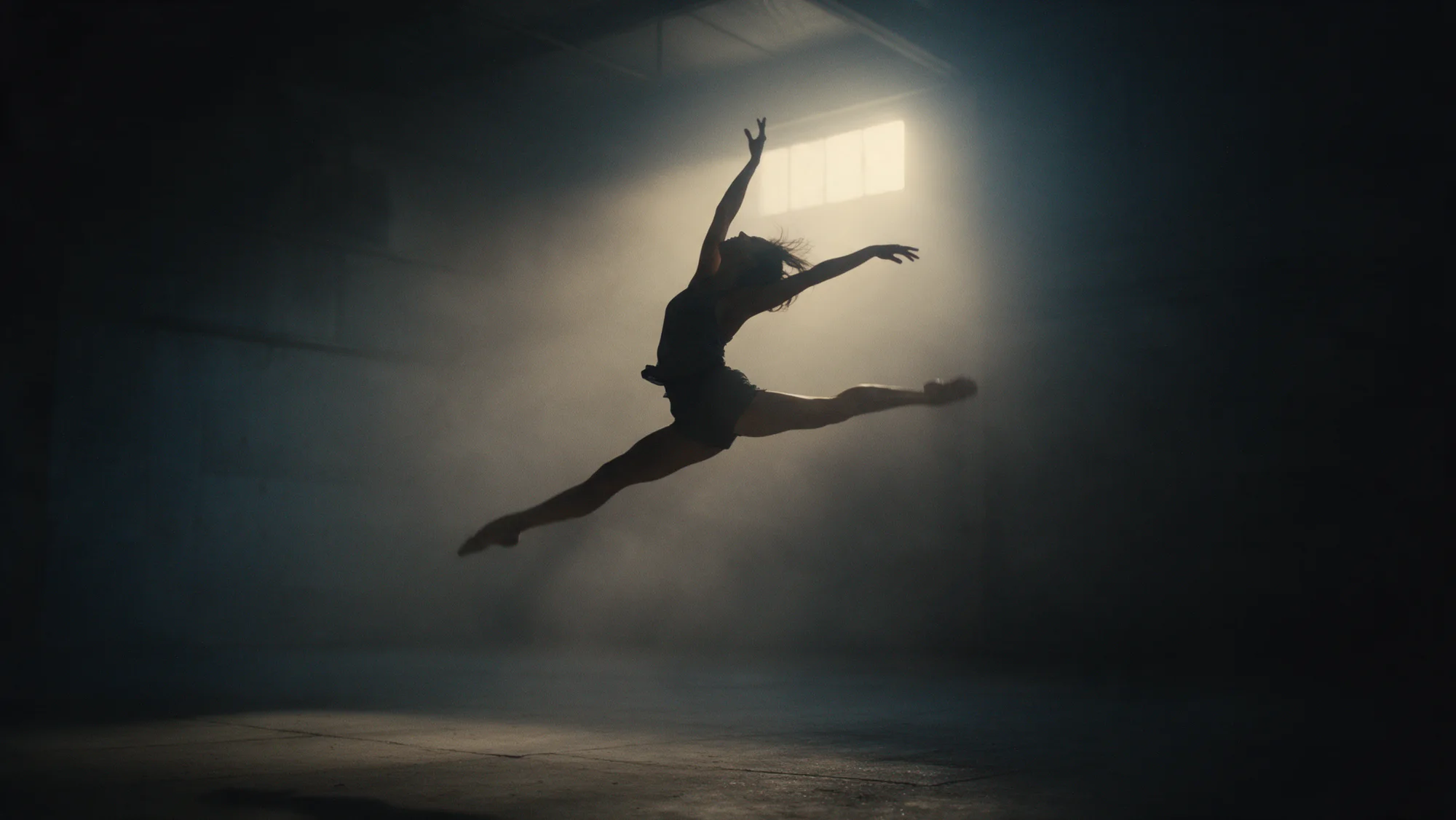 A dancer mid-leap in a hazy concrete warehouse, backlit by one hard light.
